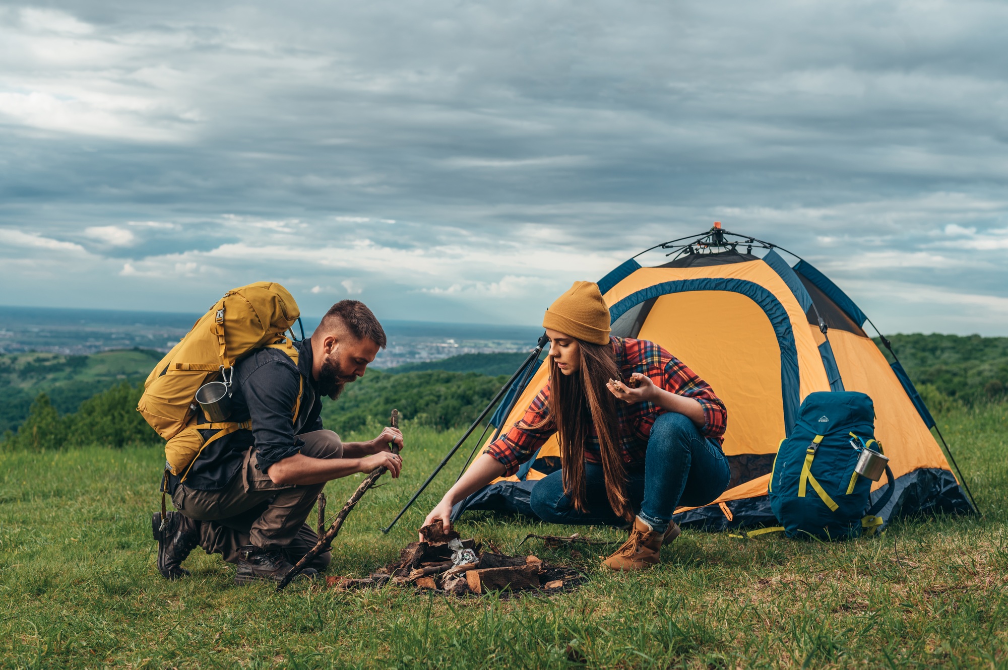 couple-of-campers-lighting-a-fire-while-setting-up-the-camp-tent.jpg